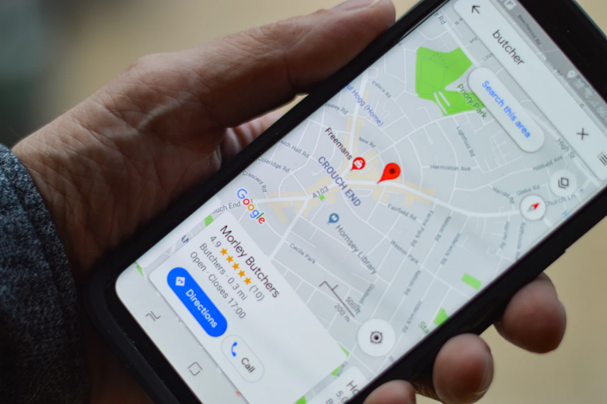 Smartphone in der Hand mit Google-Maps-Suchergebnis für ein lokales Geschäft